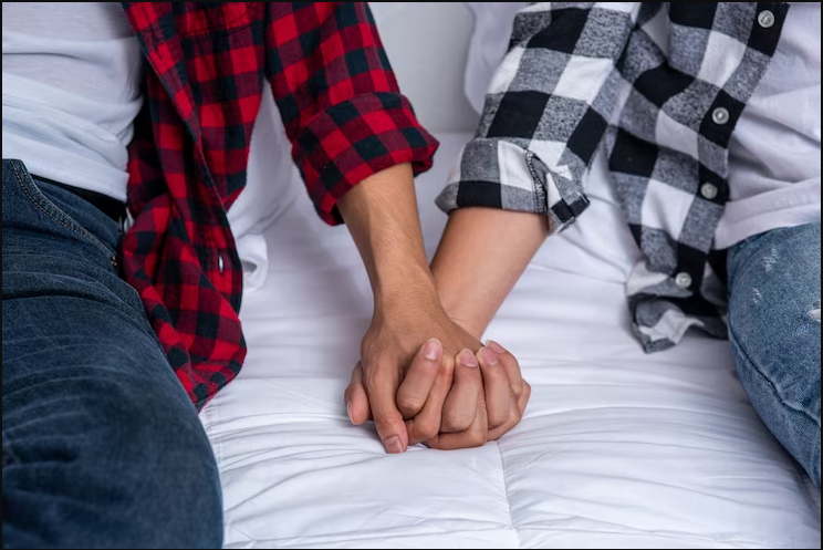 Two members wearing flannel shirt holding hands